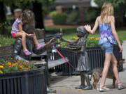 Lucy Tibbits, right, 11, of Vancouver, her sister Christianna Tibbits, 5, and their dog, Charlie, interact with a piece of public art at Esther Short Park in August 2012.