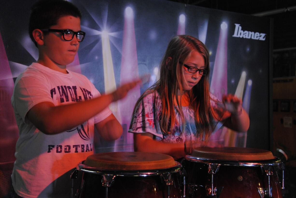 Twin brother and sister Ben and Alee Martin, 11, show off a drumming pattern they learned in school at one of the many interactive displays inside the Clark County Fair's &quot;Rock U: The Institute of Rock 'n' Roll&quot; exhibit.