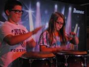 Twin brother and sister Ben and Alee Martin, 11, show off a drumming pattern they learned in school at one of the many interactive displays inside the Clark County Fair's &quot;Rock U: The Institute of Rock 'n' Roll&quot; exhibit.