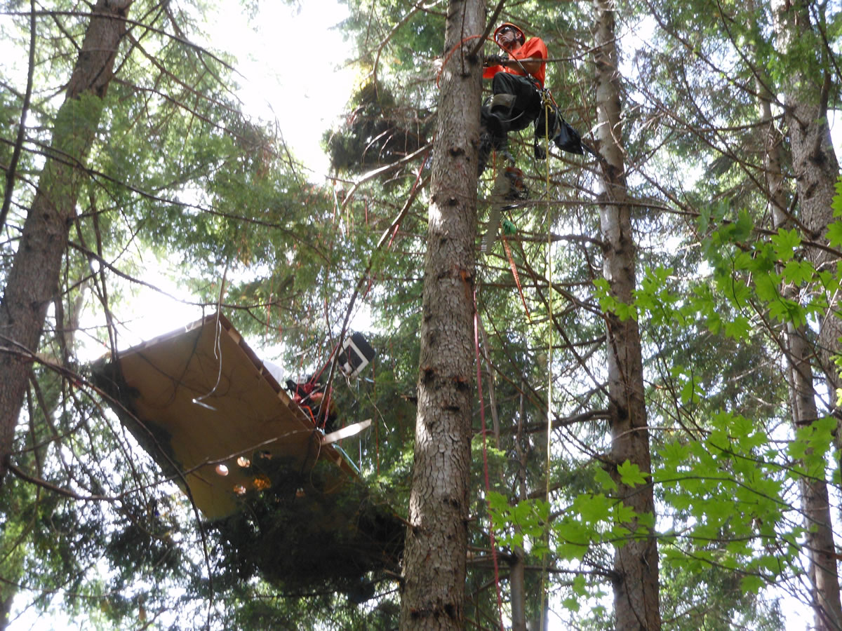 Jess Seekins of the Volcano Rescue Team sets up a rope system to help Joe Barbera get down from his stranded lawn chair, anchored to a wooden deck.