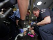 Vancouver firefighter-paramedic Mark Bennett, right, tries to find a usable vein on a female patient who collapsed March 1 during a cigarette break outside Lifeline Connections, where she was in treatment for heroin addiction.