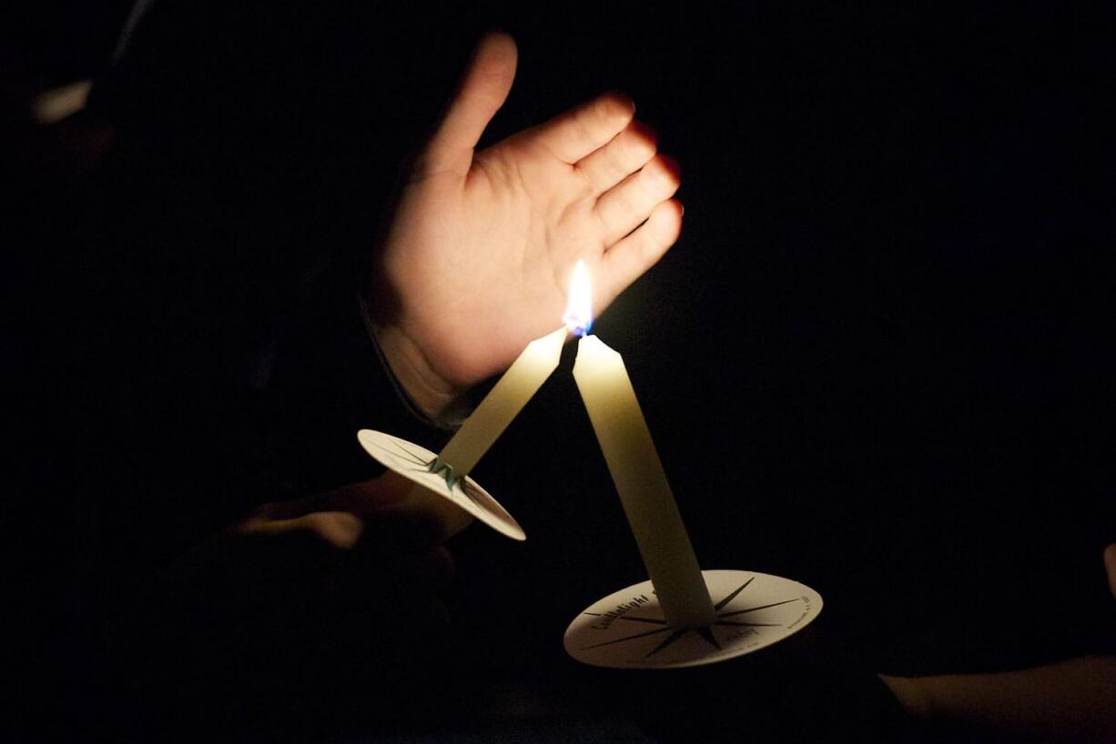 Family members of Tanner Trosko help light candles during a vigil honoring the teen, who died in a car wreck Wednesday.