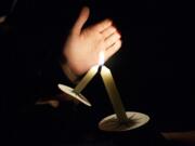 Family members of Tanner Trosko help light candles during a vigil honoring the teen, who died in a car wreck Wednesday.