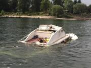 A cabin cruiser sits partially submerged after it took on water and was abandoned near Kelley Point in the Columbia River on Monday.