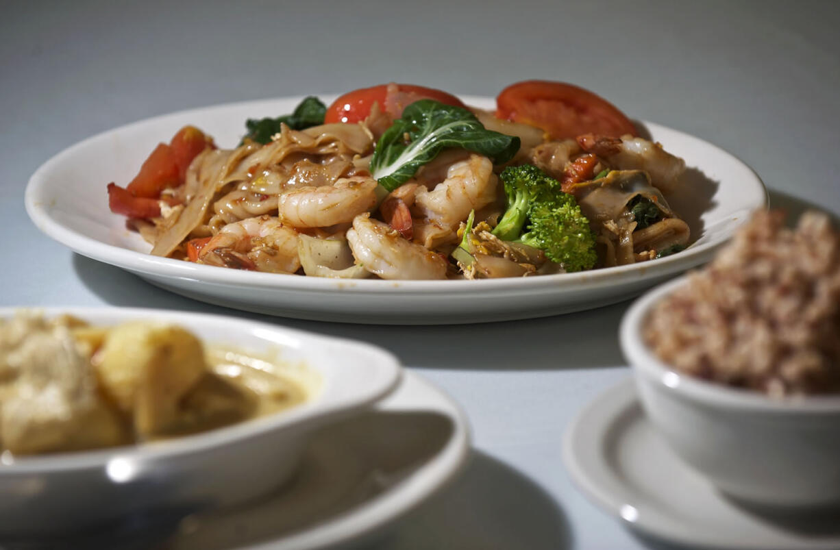 The Pad Kee Mao, or Drunken Noodles, with shrimp, center, and the Khao Pad Kari, or Yellow Curry, with chicken and a Thai Ice Tea at Keo Thai West.