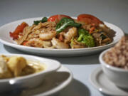 The Pad Kee Mao, or Drunken Noodles, with shrimp, center, and the Khao Pad Kari, or Yellow Curry, with chicken and a Thai Ice Tea at Keo Thai West.