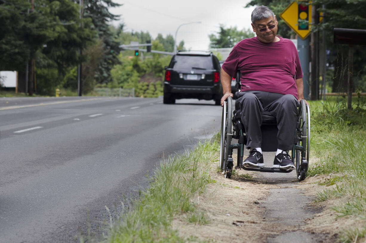 Jesse Magana struggles along the overgrown sidewalk on beside Northeast 112th Avenue in Vancouver.