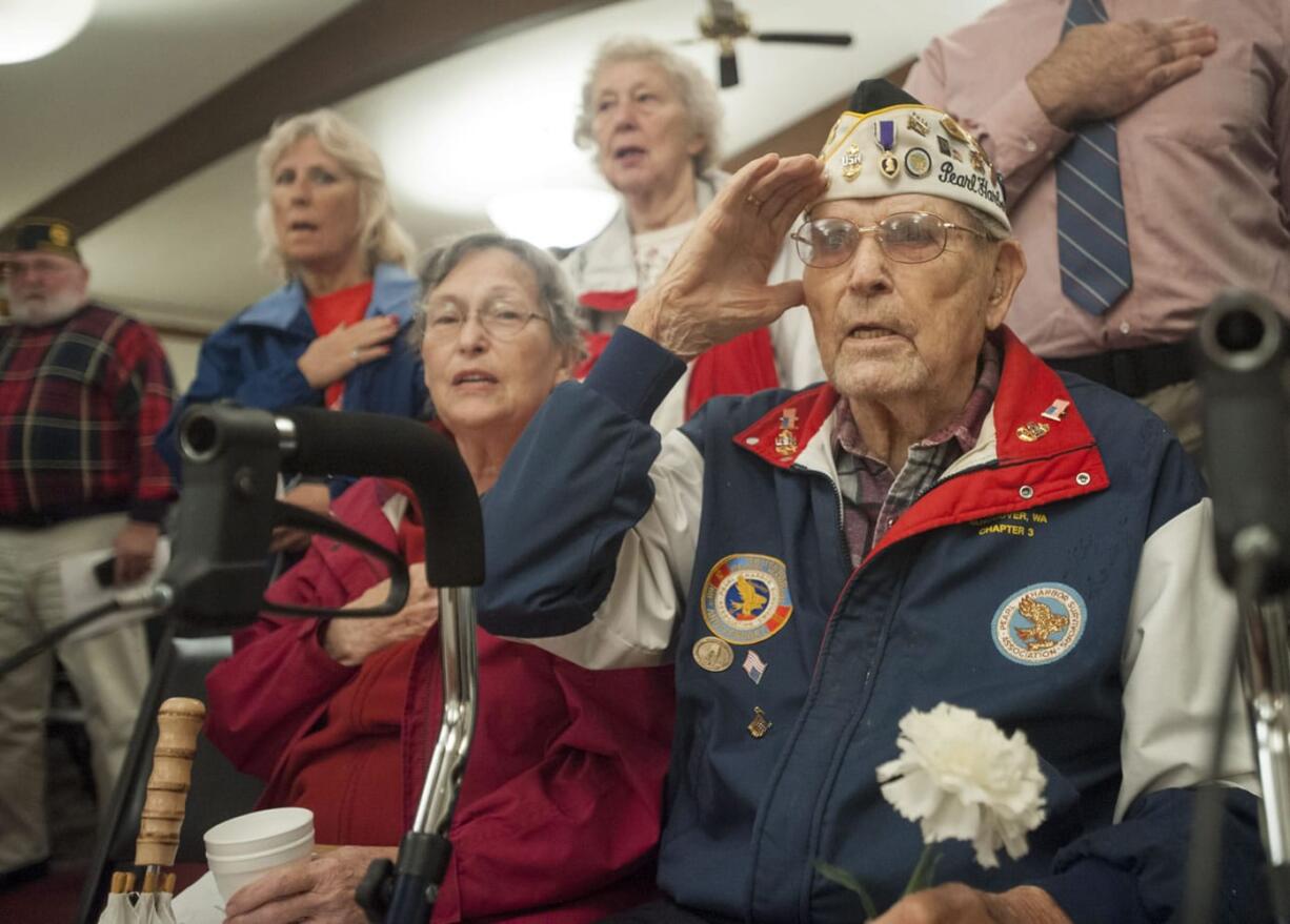 Pearl Harbor survivor Paul Johnson salutes Monday morning during the Pledge of Allegiance at the observance commemorating the 74th anniversary of the attack on Pearl Harbor. Wife Margaret Johnson is next to him.