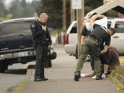 Vancouver Police officers search two men detained on St. Johns Boulevard during a search for an individual in the Rose Village neighborhood.