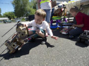 Jake Swan, 4, left, looks at a toy helicopter being sold by Jonathan Arnot, 7, right, during the Rose Village Neighborhood Association's yard sale at Memorial Lutheran Church earlier in June.