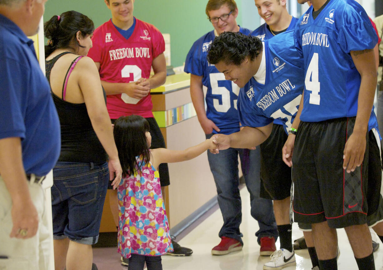 Steven Lane/The Columbian
Jafar Tiatia from Evergreen High School meets Dahlia Padilla, 3, and her mom Tracey Padilla at Shriners Hospital in Portland. Dahlia's sister is a patient at the hospital.