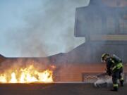 A Vancouver firefighter cuts a hole in the roof of Who Song and Larry's restaurant on Wednesday.