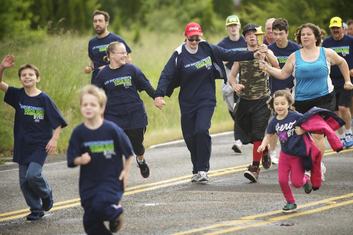 From left, holding hands, Lynnadele Schoeneberg, Fiona Wimber, Dennis Dole Jr. and Deanna Sanders finish the 11-mile Law Enforcement Torch Run on Wednesday.