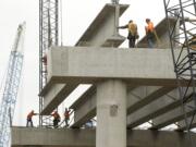 Workers from Max J. Kuney Co. lift a concrete girder onto bridge supports Tuesday as part of the Salmon Creek Interchange Project.