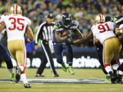 Seattle Seahawks' running back Marshawn Lynch (24) leaps as he carries the ball against San Francisco 49ers' Eric Reid (35) and Ray McDonald (91) in the first half of an NFL football game, Sunday, Sept. 15, 2013, in Seattle.