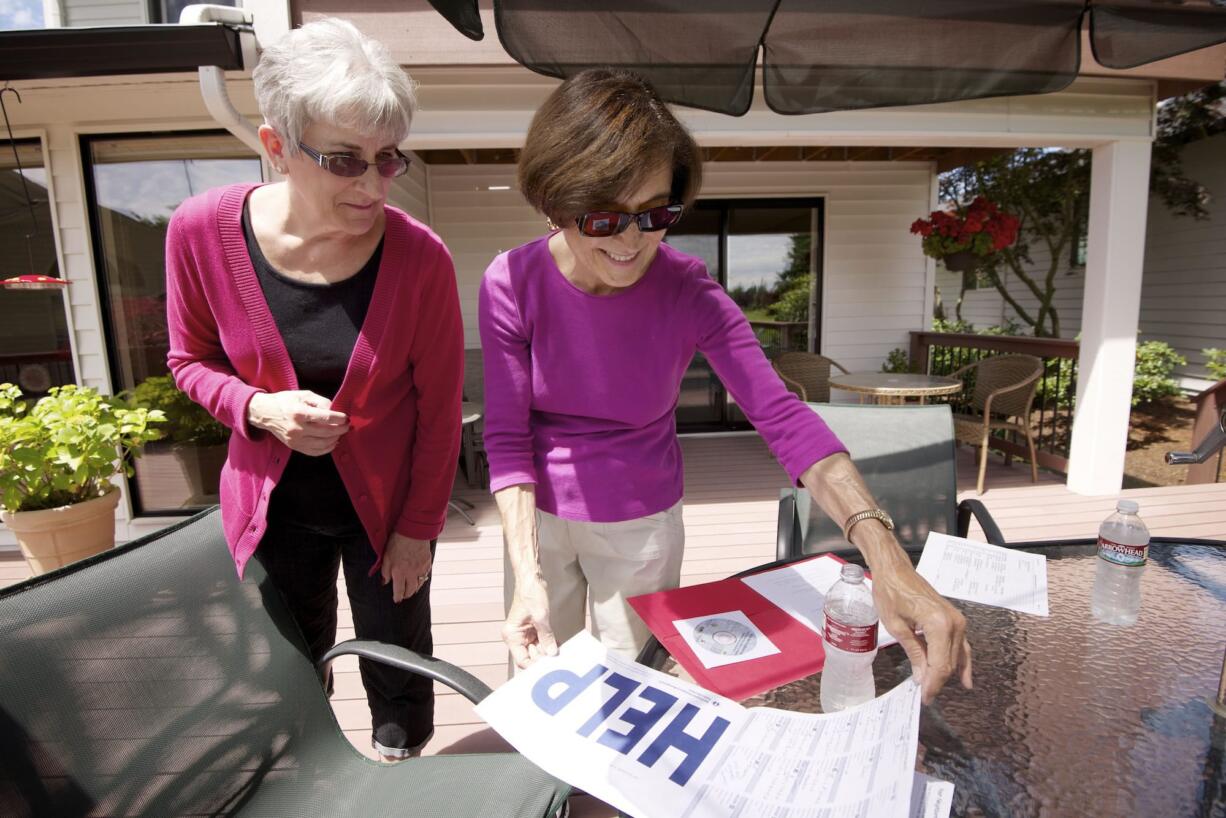 Barbara Gassin, right, and Vikki Hamilton, chair of the Fairway Village Neighborhood Watch committee, flip through the materials of the Map Your Neighborhood program.