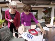 Barbara Gassin, right, and Vikki Hamilton, chair of the Fairway Village Neighborhood Watch committee, flip through the materials of the Map Your Neighborhood program.