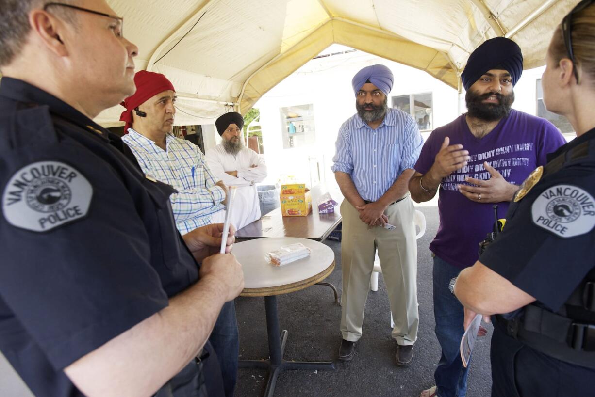 Chris Sutter, left, and Amy Foster of the Vancouver Police Department visit the Guru Ramdass Sikh temple Wednesday to discuss security with temple leaders, from left, Sarabjeet Teja, Tajinder Singh, Gurjit Singh and Pawneet Sethi.