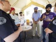 Chris Sutter, left, and Amy Foster of the Vancouver Police Department visit the Guru Ramdass Sikh temple Wednesday to discuss security with temple leaders, from left, Sarabjeet Teja, Tajinder Singh, Gurjit Singh and Pawneet Sethi.