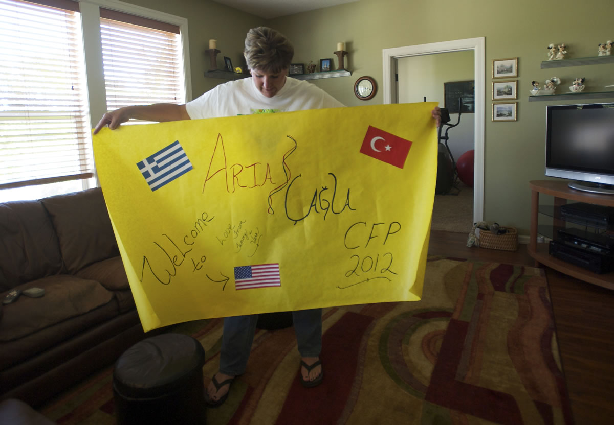 Tammy Haas displays a sign she and her husband, Vern, prepared to greet two Cypriot students, one Greek and one Turkish, they are hosting this month at their Battle Ground home.