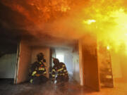 Columbian reporter Emily Gillespie (L) takes part in a fire department training exercise in Camas Tuesday April 21, 2015. The Camas-Washougal Fire Department burnt down a house for training purposes.