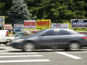 Motorists pass by political campaign signs at Northeast 134th Street and Northeast Highway 99 on Monday.