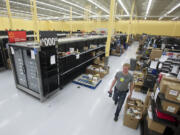 Assistant manager James Carlson walks past as employees stock the shelves of the new Walmart Neighborhood Market, planned to open July 17 at Vancouver Plaza.