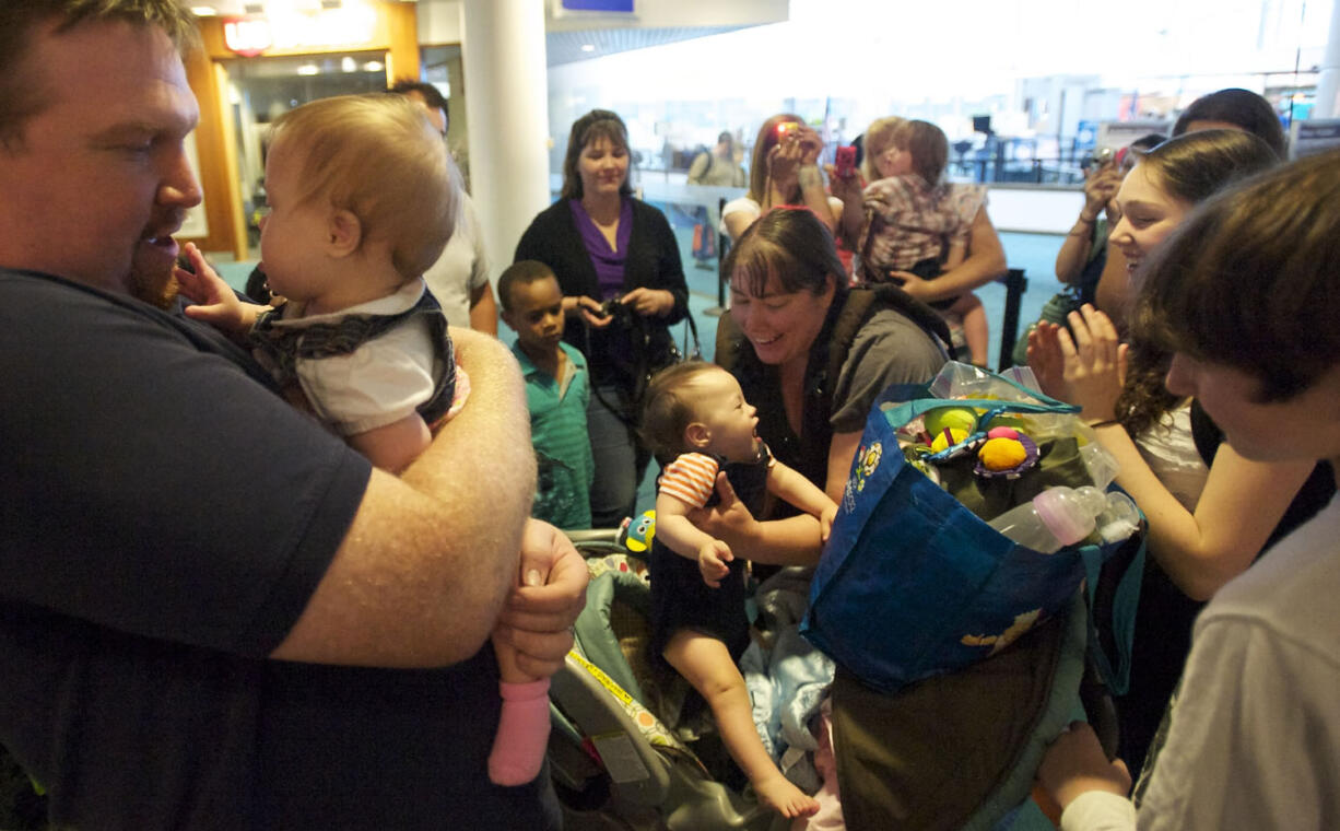 Proud Papa Mark Jenks cuddles his new daughter, Veronika, 12 months, while his wife Rebecca, background center, picks up their new son Gavyn, 10 months. Veronika seems to like her dad's beard.