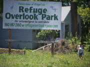 A woman cuts grass Wednesday near a sign at the property for the proposed Overlook Park in Ridgefield.