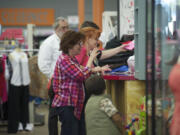 Becky Mauro of San Francisco, waves goodbye to staff at Spanky's consignment shop while accompanying friend Claudia Ross of Vancouver, who was attempting to sell clothing at the store on Wednesday. Years of economic stagnation has stretched household budgets painfully thin.