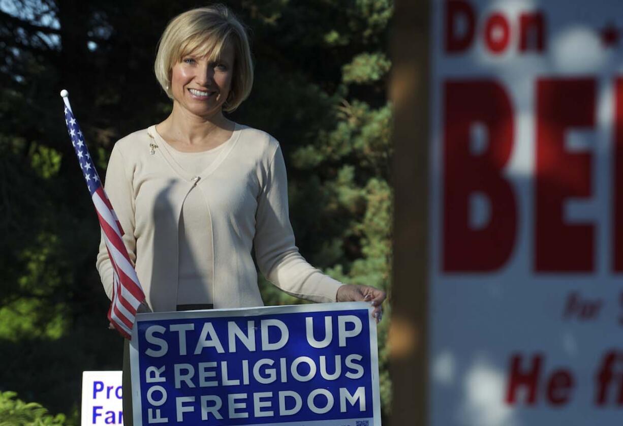 Lisa Schmidt stands Wednesday evening amid the yard signs in the front yard of her Ridgefield home.