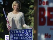 Lisa Schmidt stands Wednesday evening amid the yard signs in the front yard of her Ridgefield home.