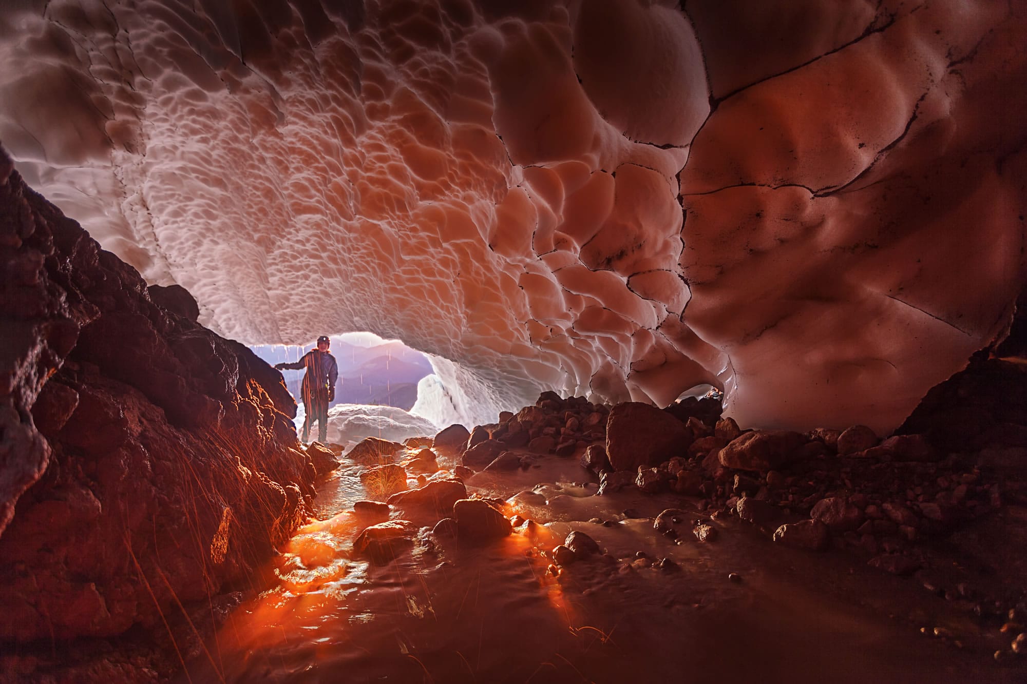 Brent McGregor
The early morning sun lights up the lower entrance of Pure Imagination, a cave in the Sandy Glacier on Mount Hood. At top, after Jared Smith set up the rope system, Eddy Cartaya makes an early-morning descent as lights from an OPB-TV crew illuminate the interior of the moulin.