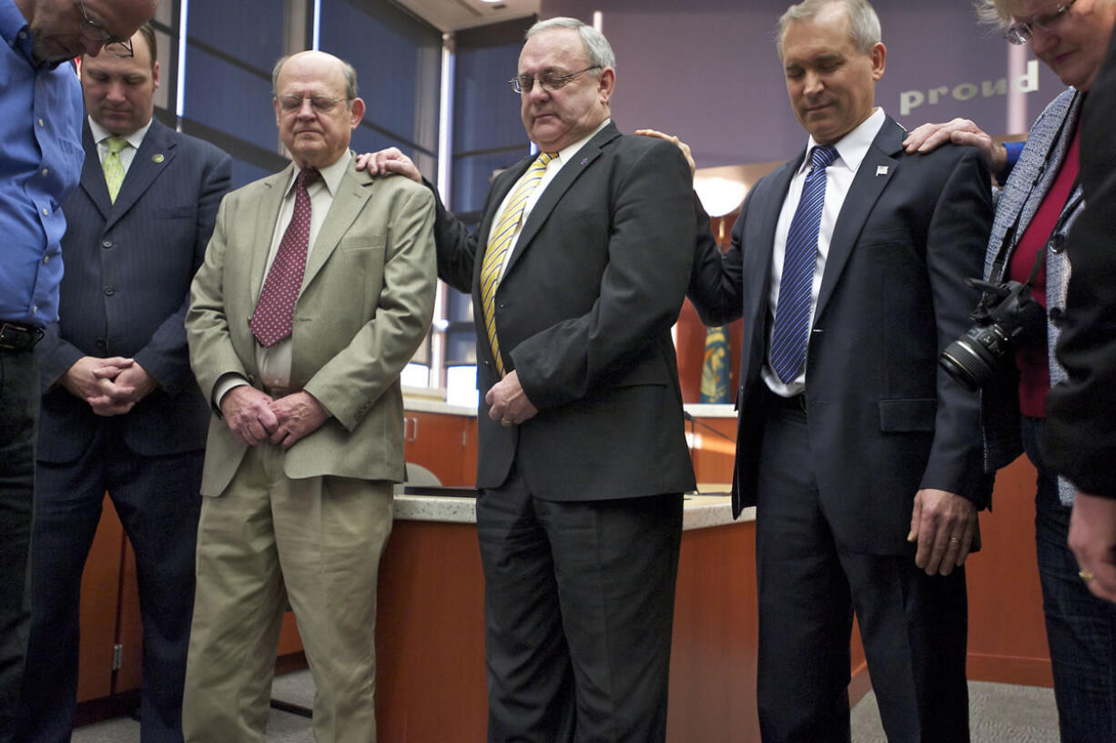 Clark County Commissioners Tom Mielke, center, and David Madore, second from right, and Clark Public Utilities Commissioner Jim Malinowski, third from left, pray after taking the oath of office with a group that includes fellow commissioner Steve Stuart, second from left, at the County Services Building.