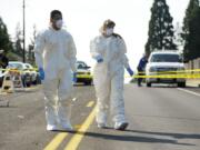 Skills Center student interns Edgar Quintero, 17, left, and Clair Becker, 18, wear protective gear to prepare to search a Dumpster for evidence at a homicide scene in Northeast Hazel Dell on Monday.