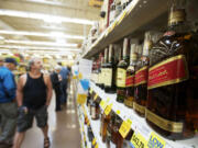 Shoppers look over the liquor choices in the grocery section at the Grand Central Fred Meyer store in Vancouver.