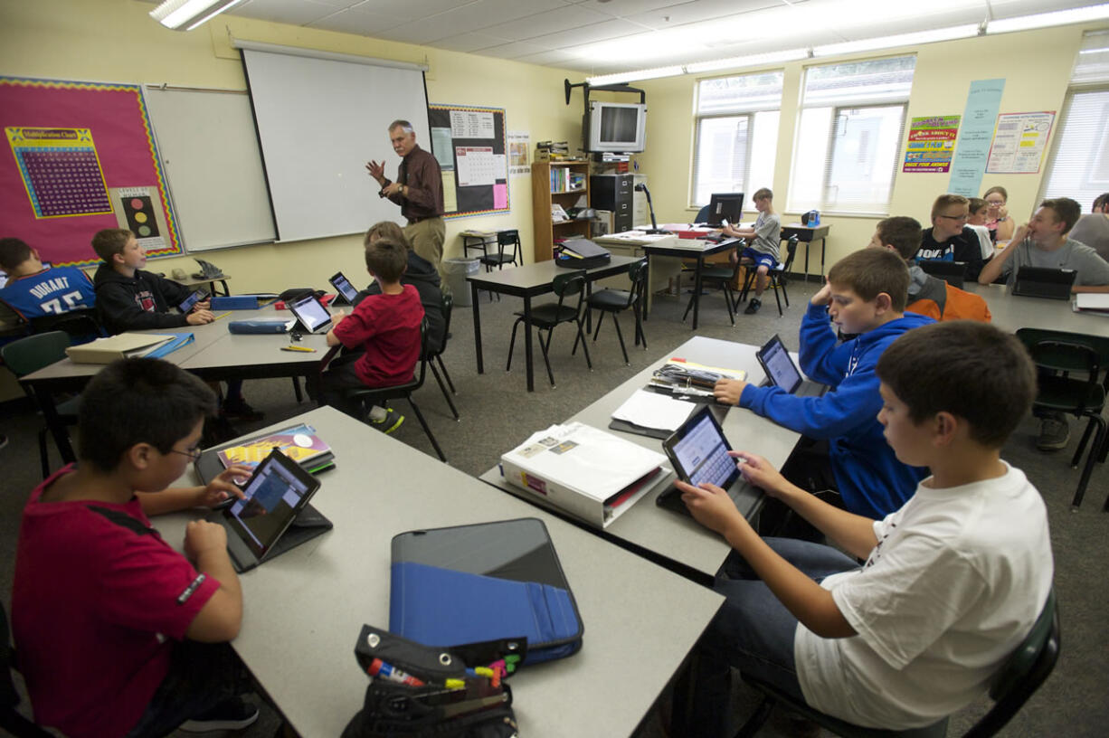 Students in Mike Holland's math class at La Center Middle School solve math problems while Holland teaches at the front of the class.