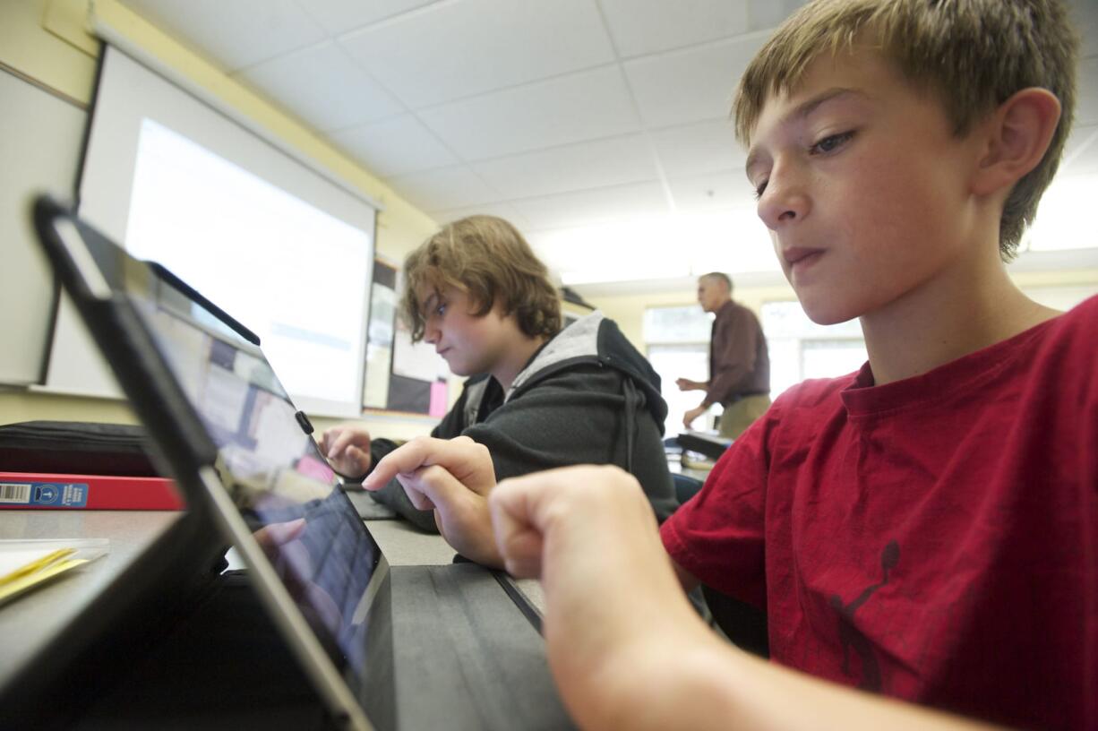 Jacob Russell, 12, right, and Wyatt Elton, 13, use iPads to solve math problems in Mike Holland's seventh-grade math class.