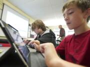 Jacob Russell, 12, right, and Wyatt Elton, 13, use iPads to solve math problems in Mike Holland's seventh-grade math class.