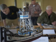 A model tug boat sits in the foreground as judges (background from left) Terry Werdel, Mark Peterson and Mike LaLone look over other entries during the IPMS LT.