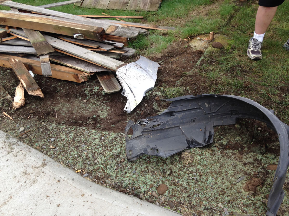 Part of a bumper and some other car wreckage remained in Jerry Sutherland's front yard Friday after a car sped through the roundabout at N.E. 32nd Circle and crashed into his fence.