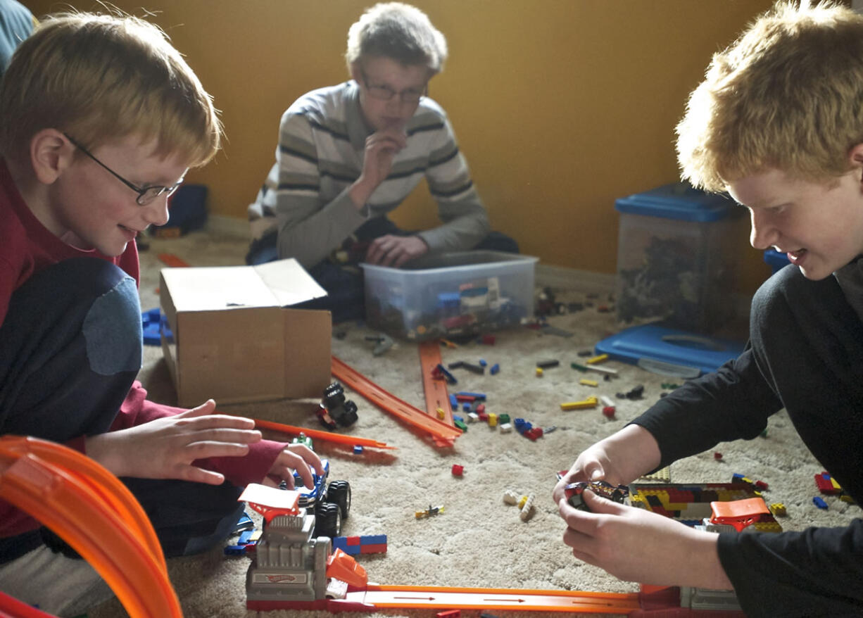 Brothers Joe, 10, from left, Marcus, 14, and Alex, 13, who were adopted by a Clark County couple, play at their home Oct. 29. The Children's Administration has sent letters to families requesting that they voluntarily agree to reduce their monthly adoption support payments.