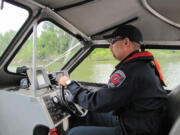 Fire Captain Abe Rommel steers the rescue boat along the Ridgefield marina and monitors the boat's depth sounder to avoid areas where the water is too shallow.