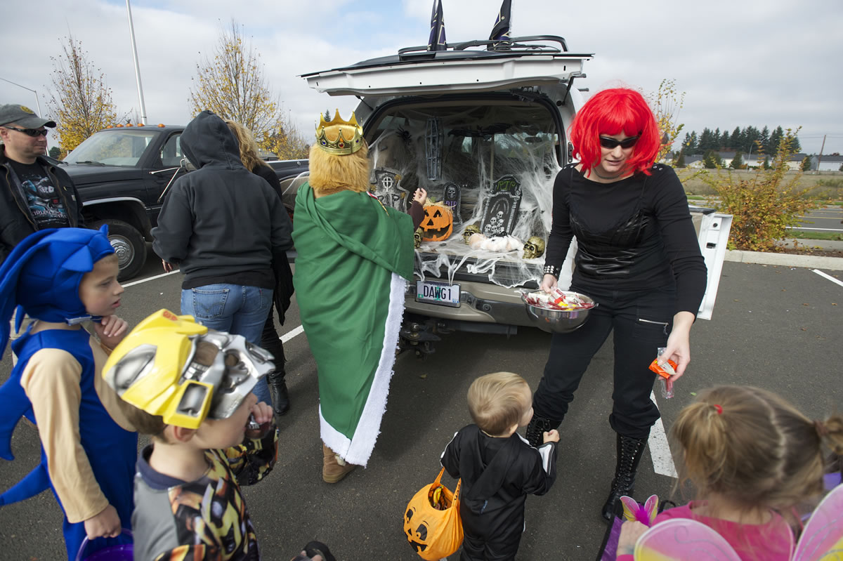 Amber Schlesser, right, with the Oregon Air National Guard's 142nd Fighter Wing, hands out Halloween candy during Saturday's Trunk or Treat event at the Armed Forces Reserve Center in Vancouver.