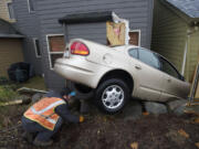 Carlos Urbina of Chuck's Towing of Washougal works to remove a car that crashed Sunday afternoon into this house at 3031 N.W.