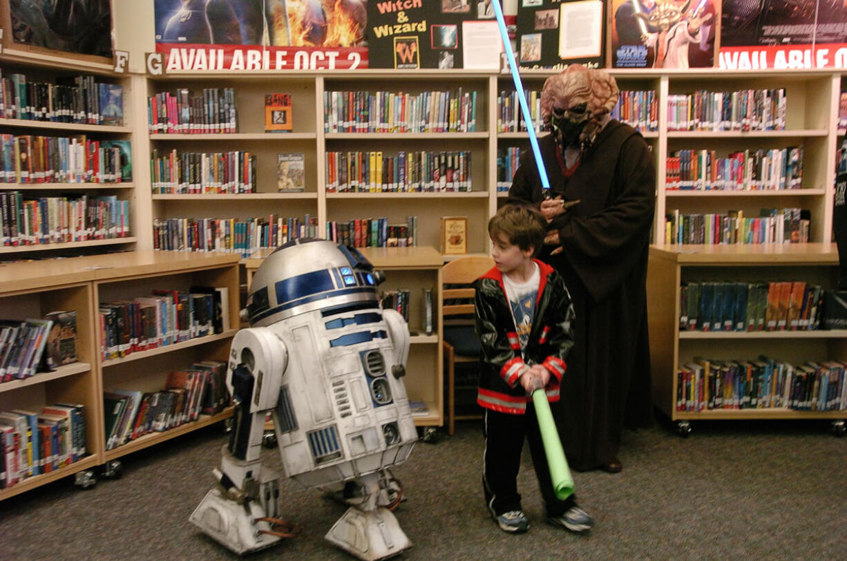 Patty Hastings/The Columbian
Ricky Gartner, 5, looks back at R2-D2 after posing with him, as another creature looks on, at Shahala Middle School's sci-fi family night and book fair.