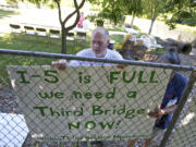 Robert Ross, of Vancouver, and Lola Smythe, of Portland, hang a sign during a gathering showcasing alternatives to the failed Columbia River Crossing project in Vancouver last week.