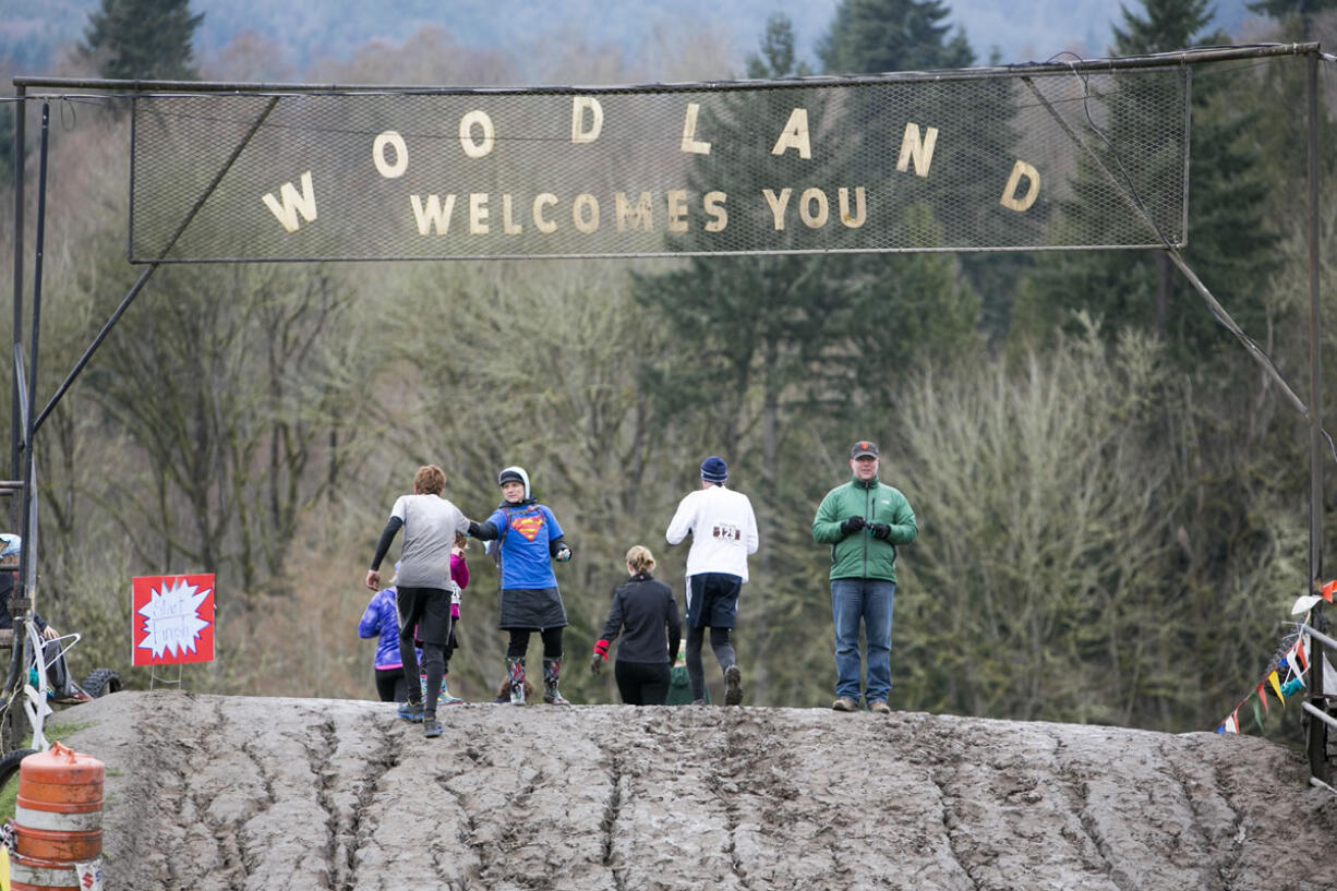 Racers receive bracelets as they cross over the start/finish line, above, and continue on the course during the March Muddy Madness event Saturday at Woodland MX Park.