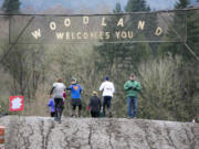 Racers receive bracelets as they cross over the start/finish line, above, and continue on the course during the March Muddy Madness event Saturday at Woodland MX Park.