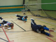 Nov Gnik, left, and his teammates drop to their sides and block a shot during goalball practice at the Washington State School for the Blind on Monday. The group is getting ready for the 2013 National Goalball Championship tournament, to be held at McLoughline Middle School Thursday through Saturday.